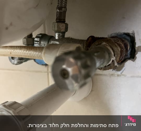 צינורות מתכת וברז מתחת לכיור